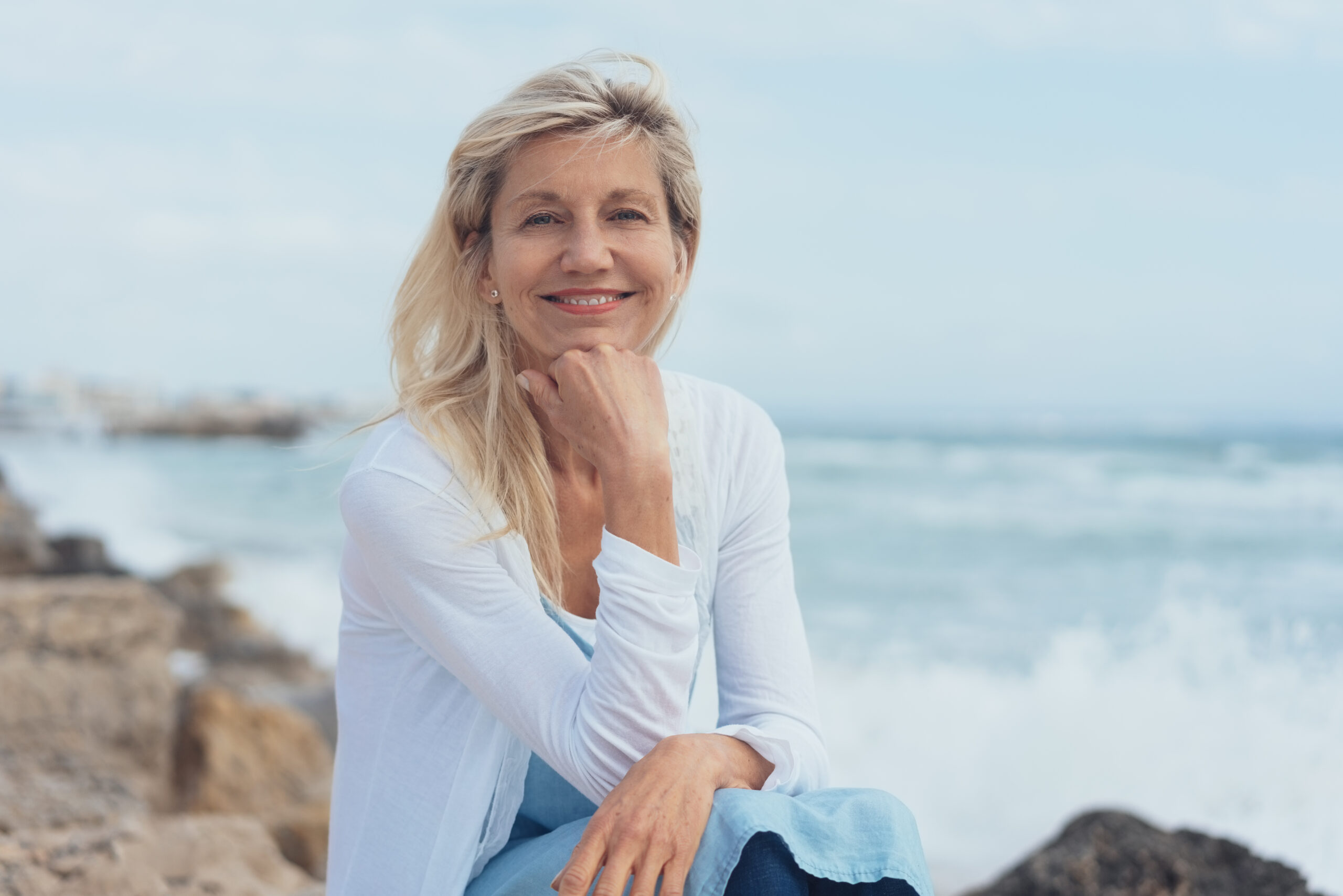 Eine Frau sitzend an einem steinigen Strand